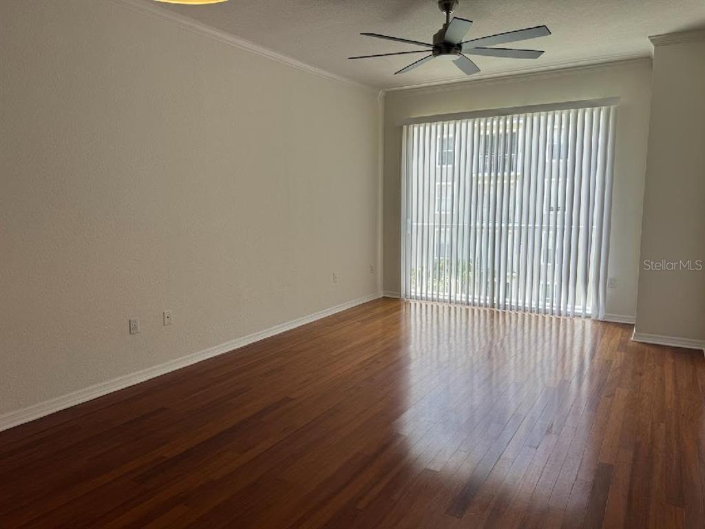 An empty living room features hardwood floors, a ceiling fan, and vertical blinds on sliding doors — 700 S HARBOUR ISLAND BOULEVARD UNIT 422, TAMPA, FL