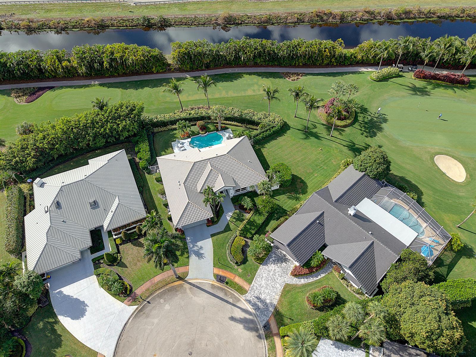 An aerial view shows three houses with pools situated along a golf course and canal — 7946 Shelby Circle, Boca Raton FL 33496, BOCA RATON, FL