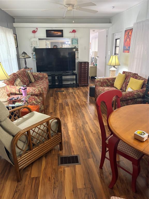 A living room features floral sofas, a large television, a rattan chair, and wood-look flooring — 723 ROMA ROAD, VENICE, FL