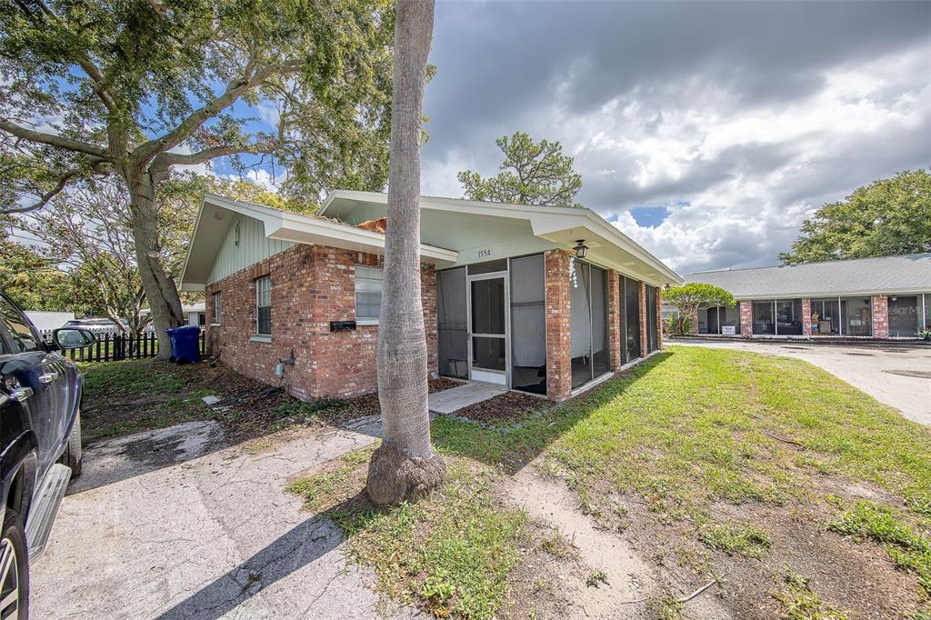 A single-story brick building with a screened-in porch and a palm tree in front — 153 NEW YORK AVENUE, DUNEDIN, FL