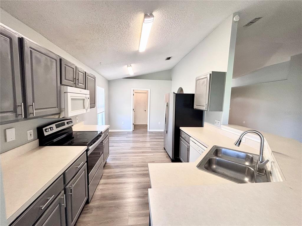 A kitchen with gray cabinets, stainless steel appliances, and light-colored countertops — 15937 WILKINSON DRIVE, CLERMONT, FL