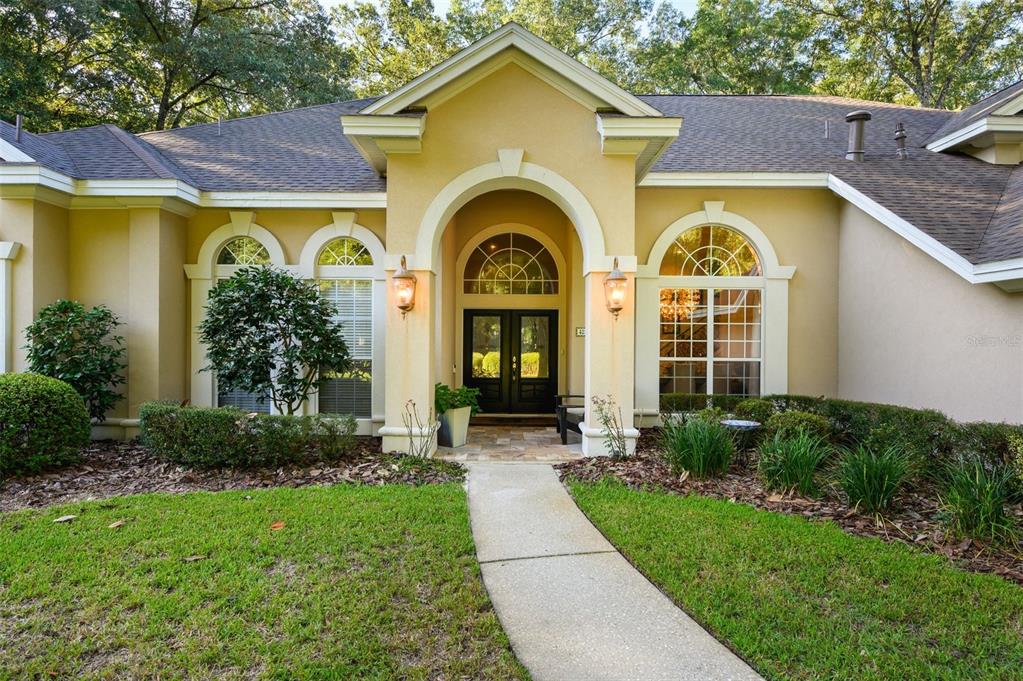 A tan single-story house with a covered arched entryway, double front doors, and arched windows — 4239 SW 104TH TERRACE, GAINESVILLE, FL