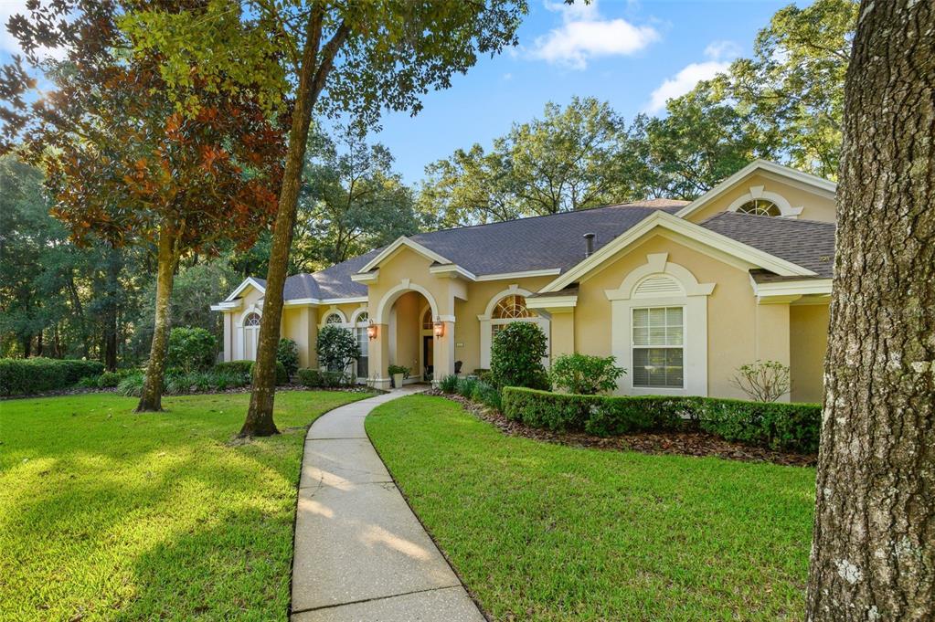 A beige single-story house with a concrete walkway leading to the front entrance — 4239 SW 104TH TERRACE, GAINESVILLE, FL