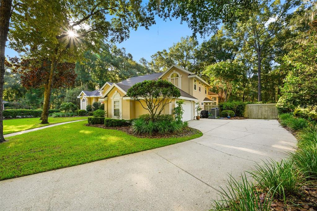 A two-story tan house with a concrete driveway and a large green lawn — 4239 SW 104TH TERRACE, GAINESVILLE, FL