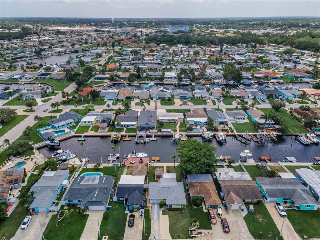 An aerial view shows a residential neighborhood with houses lining a canal and boat docks — 4946 BLUE HERON DRIVE, NEW PORT RICHEY, FL