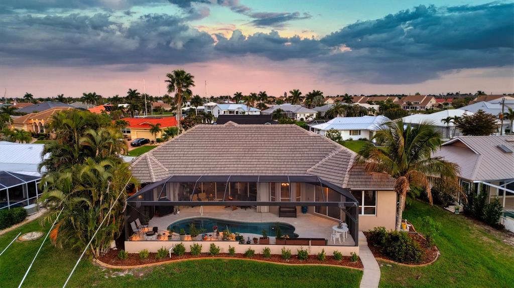 An aerial view of a house with a screened-in pool and patio at sunset — 1518 KINGLET DRIVE, PUNTA GORDA, FL