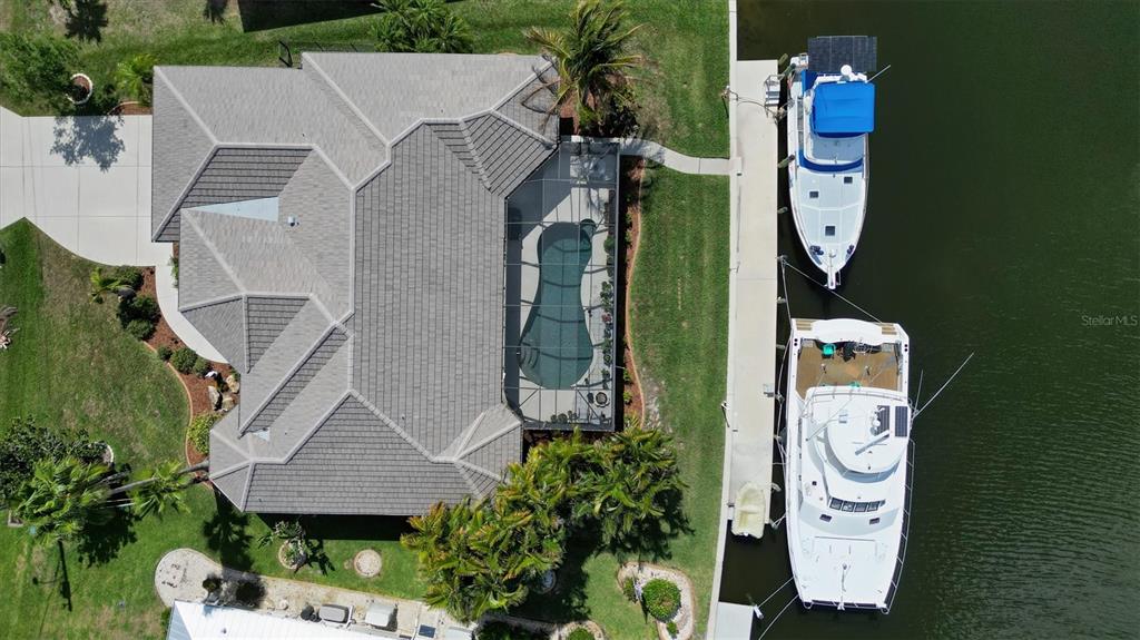 An aerial view shows a house with a pool cage and two boats docked nearby — 1518 KINGLET DRIVE, PUNTA GORDA, FL