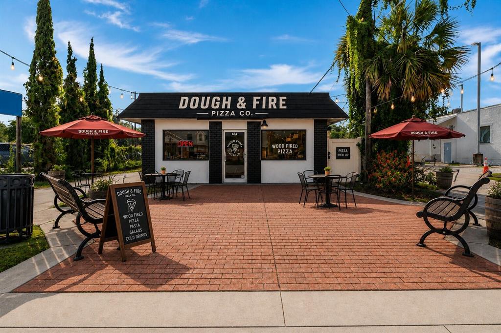 The exterior of a brick pizza restaurant features outdoor seating, red umbrellas, and signage — 124 N APOPKA AVENUE, INVERNESS, FL