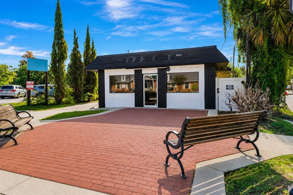 A small, white, brick-fronted building with a black roof and a red brick patio area — 124 N APOPKA AVENUE, INVERNESS, FL