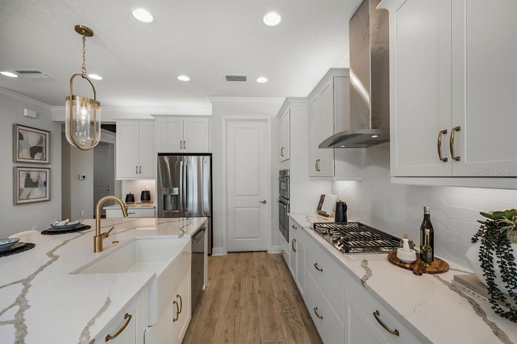A modern kitchen features white cabinetry, quartz countertops, a farmhouse sink, and stainless steel appliances — 13691 LOREDO WAY, PUNTA GORDA, FL