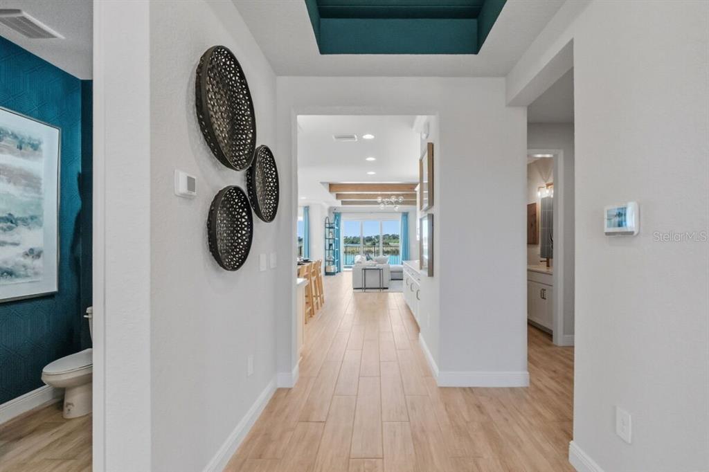 A hallway with wood-look tile flooring leads to an open living area with water views — 13691 LOREDO WAY, PUNTA GORDA, FL