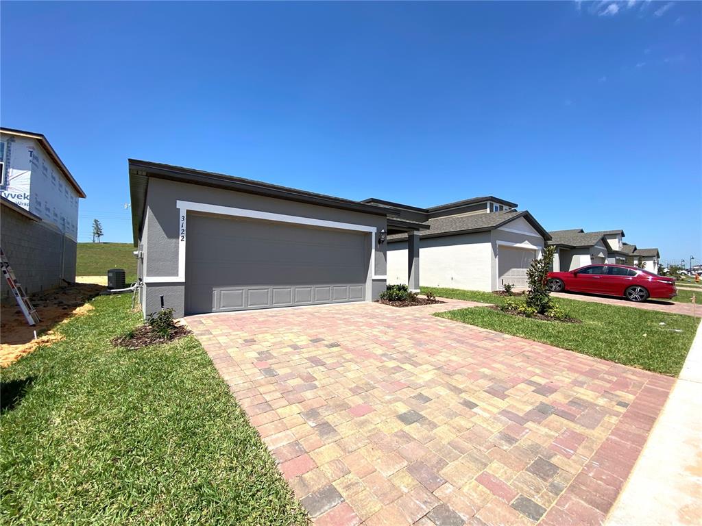 A gray house with a two-car garage and a paved driveway under a blue sky — 3122 BELLA VISTA DRIVE, DAVENPORT, FL