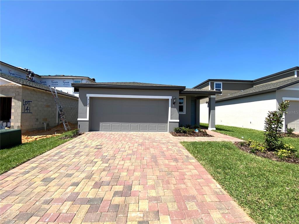 A single-story house with a gray garage and a paved driveway under a clear sky — 3122 BELLA VISTA DRIVE, DAVENPORT, FL