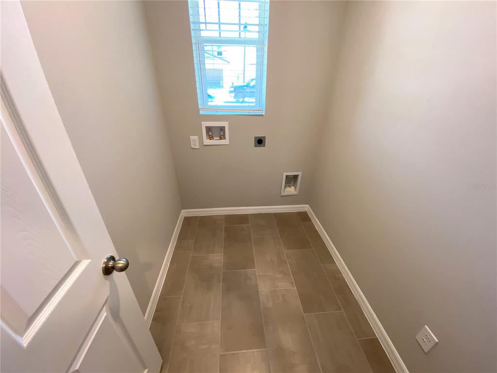 A laundry room features light gray walls, tile flooring, a window, and washer-dryer hookups — 3122 BELLA VISTA DRIVE, DAVENPORT, FL