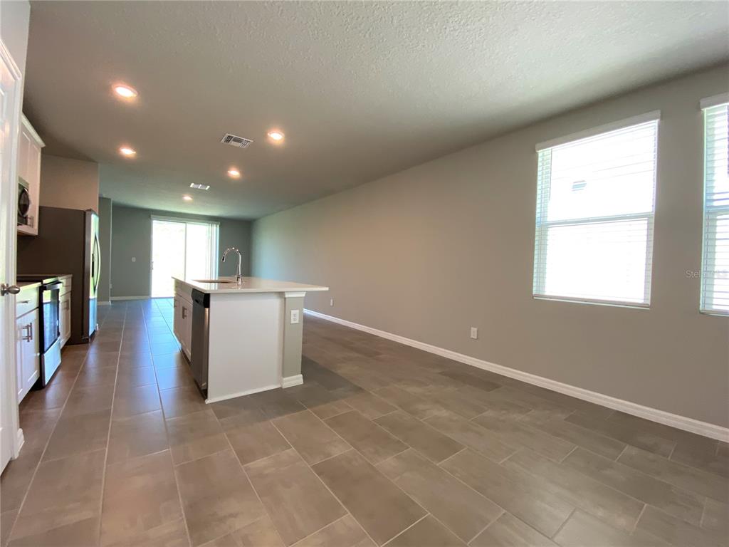 A kitchen with a white island and stainless steel appliances opens into a living area — 3122 BELLA VISTA DRIVE, DAVENPORT, FL