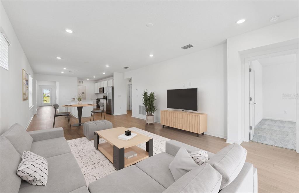 A bright, open-concept living room and kitchen area with light wood flooring and white walls — 6287 BROAD FIELD AVENUE, APOLLO BEACH, FL