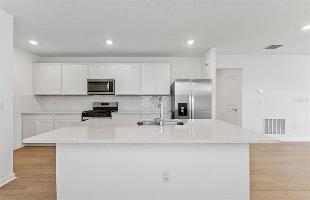 A modern kitchen features white cabinets, stainless steel appliances, and a large central island — 6287 BROAD FIELD AVENUE, APOLLO BEACH, FL