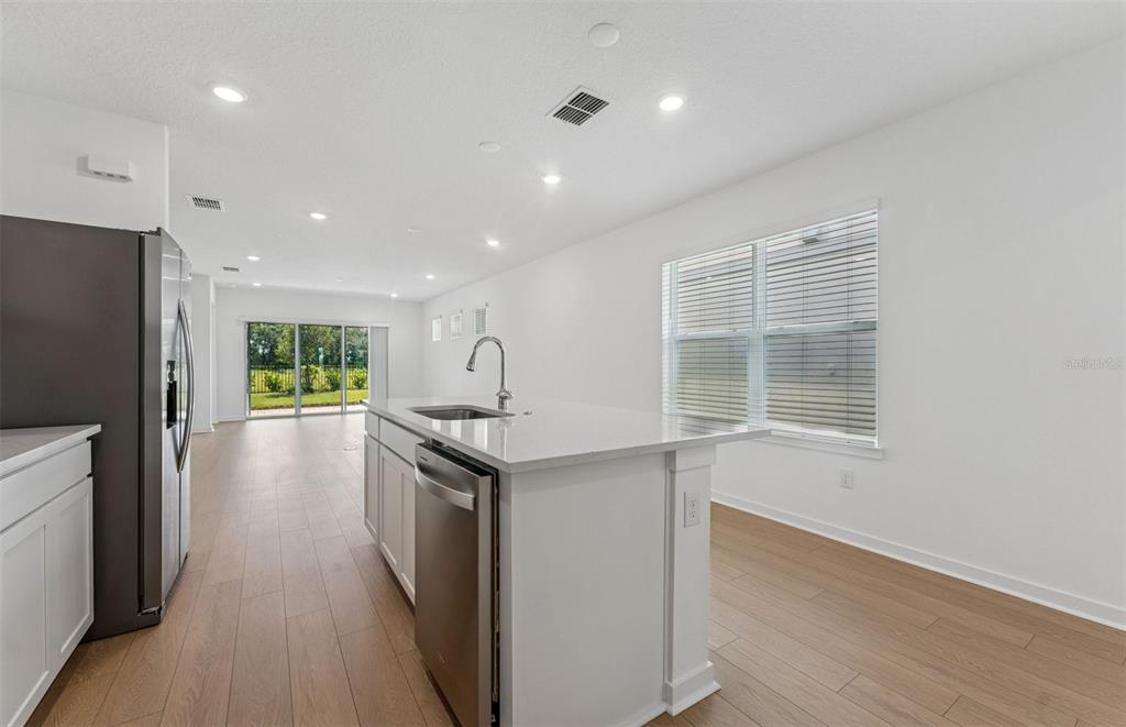 A kitchen with white cabinets, a quartz island, stainless steel appliances, and light wood flooring — 6287 BROAD FIELD AVENUE, APOLLO BEACH, FL