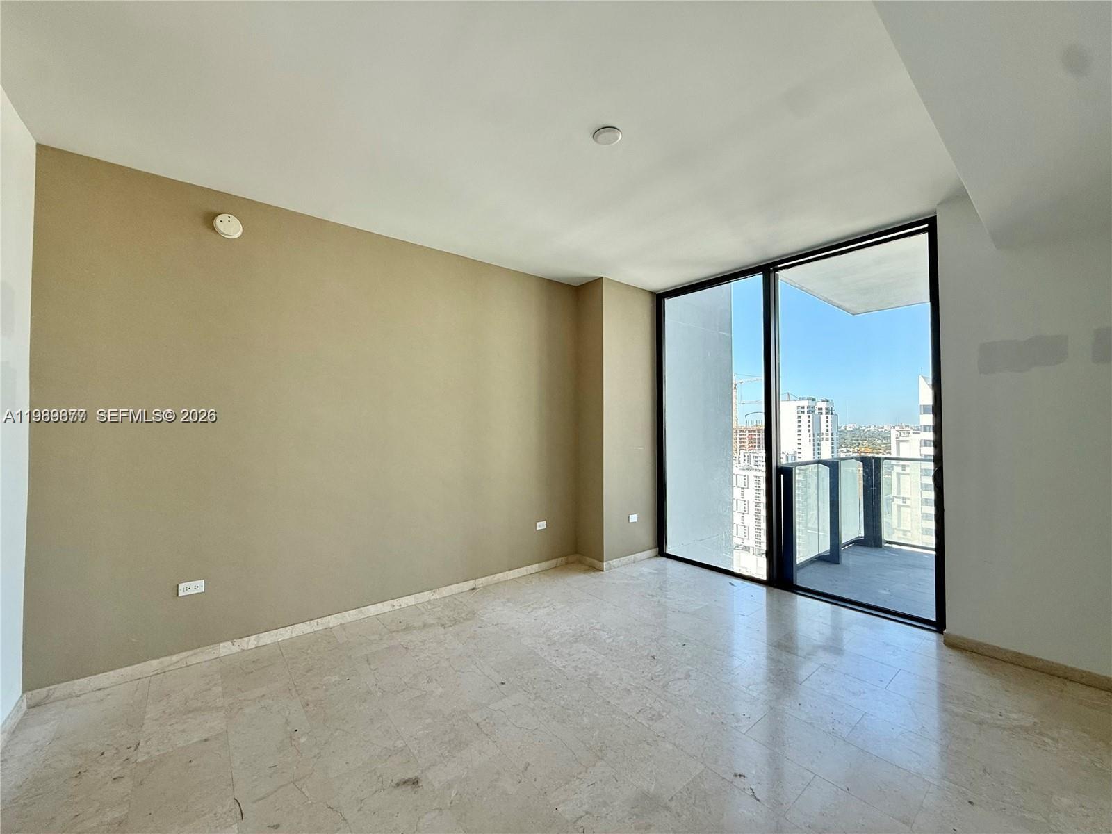 An empty room with beige walls, marble flooring, and a balcony with city views — 88 SW 7th St # 1808, Miami FL 33130, MIAMI, FL