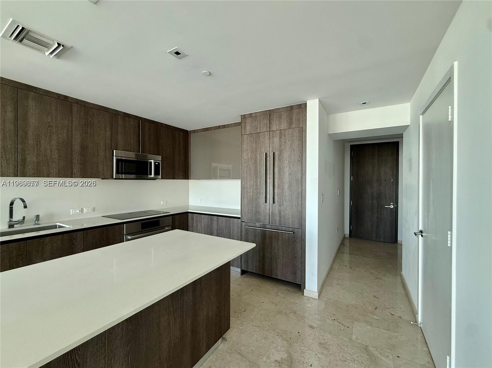 A modern kitchen features dark wood cabinetry, white countertops, and stainless steel appliances — 88 SW 7th St # 1808, Miami FL 33130, MIAMI, FL