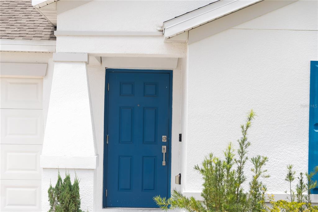 A blue front door is set into a white stucco exterior wall with a porch — 707 STAFFORA STREET, HAINES CITY, FL