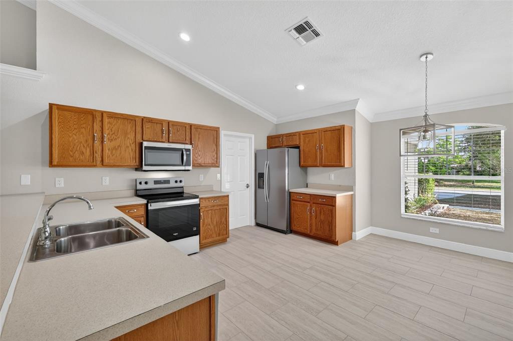 A kitchen with oak cabinets, stainless steel appliances, and light-colored tile flooring — 2294 KNOLLWOOD DRIVE, LEESBURG, FL