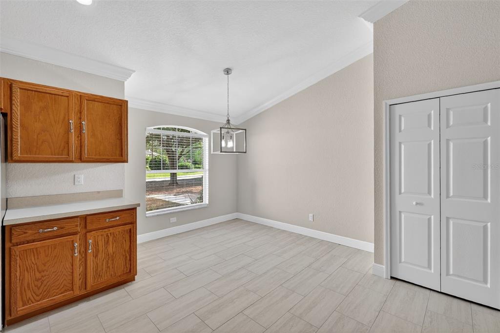 A dining area features light tile flooring, wood cabinets, a window, and a hanging light fixture — 2294 KNOLLWOOD DRIVE, LEESBURG, FL