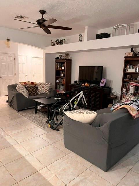 A living room features a ceiling fan, tiled floors, two gray sofas, and bookshelves — 10049 SAVANNAH BLUFF LANE, ORLANDO, FL