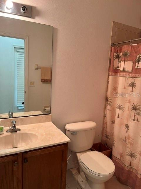A bathroom features a vanity with a sink, a toilet, and a palm-print shower curtain — 10049 SAVANNAH BLUFF LANE, ORLANDO, FL
