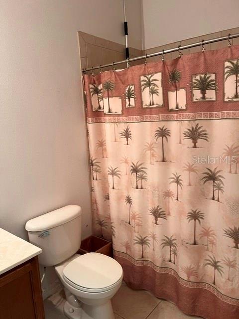 A bathroom features a white toilet next to a shower with a palm tree curtain — 10049 SAVANNAH BLUFF LANE, ORLANDO, FL