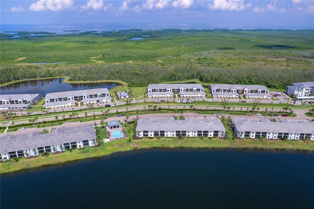 An aerial view shows multi-story apartment buildings situated near a lake and grassy wetlands — 14214 HERITAGE LANDING BOULEVARD UNIT 817, PUNTA GORDA, FL
