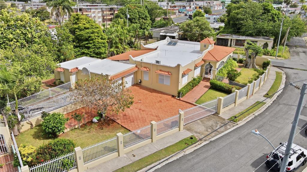 An aerial view shows a tan house with a terracotta roof, gated driveway, and landscaping — 241 B AVENUE, FAJARDO, PR