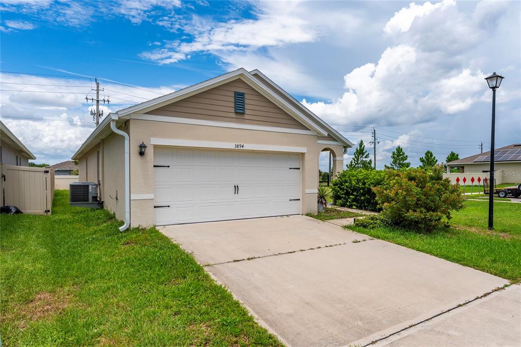 A beige house with a white garage door and a concrete driveway under a cloudy sky — 3894 SILVERSTREAM TER, SANFORD, FL