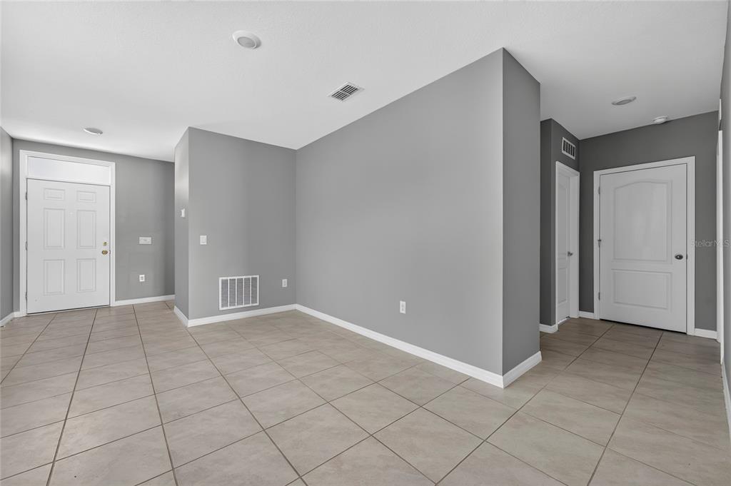 A bright entryway features light tile flooring, gray walls, two console tables, and white doors — 3894 SILVERSTREAM TER, SANFORD, FL
