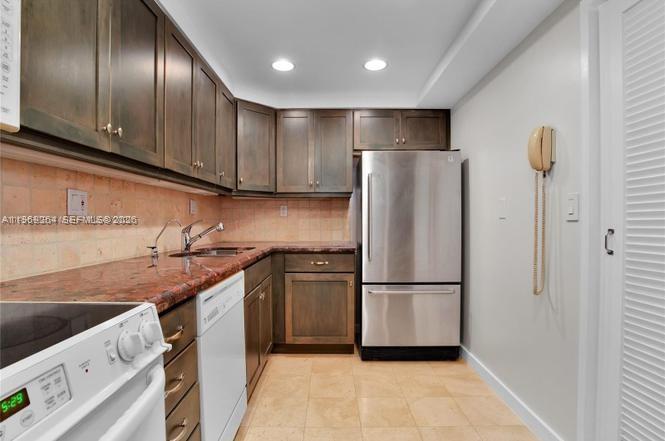 A kitchen features dark wood cabinets, a stainless steel refrigerator, and a white dishwasher — 145 SE 25th Rd # 602, Miami FL 33129, MIAMI, FL