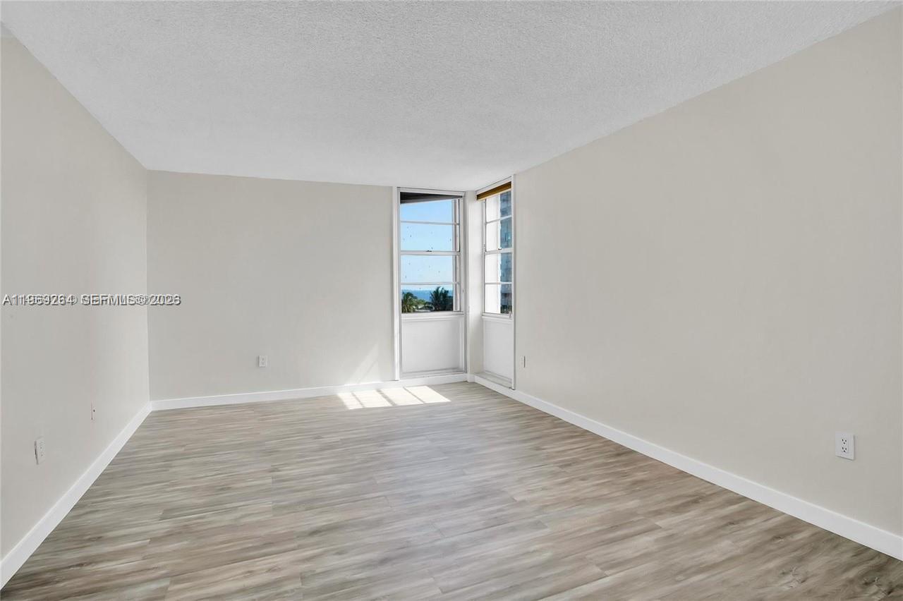An empty room features light wood-look flooring, beige walls, and a window with ocean views — 145 SE 25th Rd # 602, Miami FL 33129, MIAMI, FL