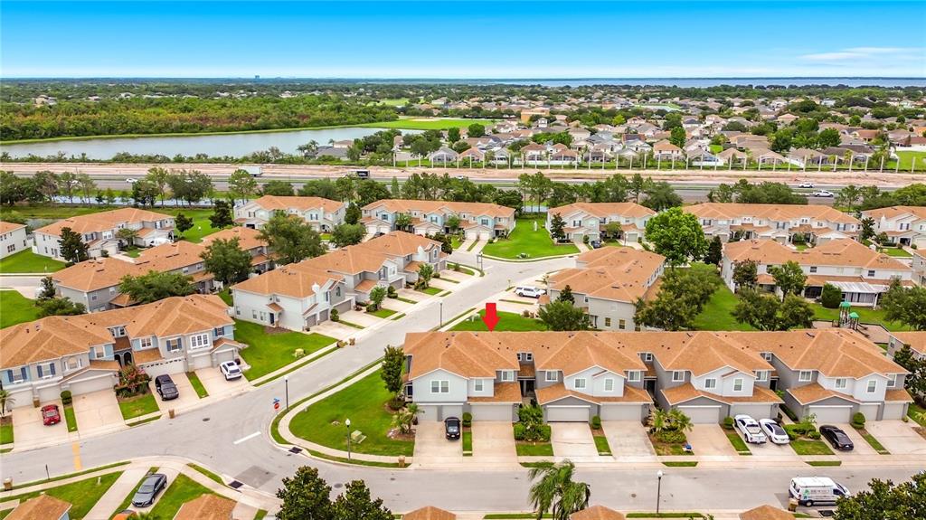 An aerial view shows a suburban neighborhood with multi-unit townhomes and a red arrow pointing down — 1009 CHALCEDONY STREET, KISSIMMEE, FL