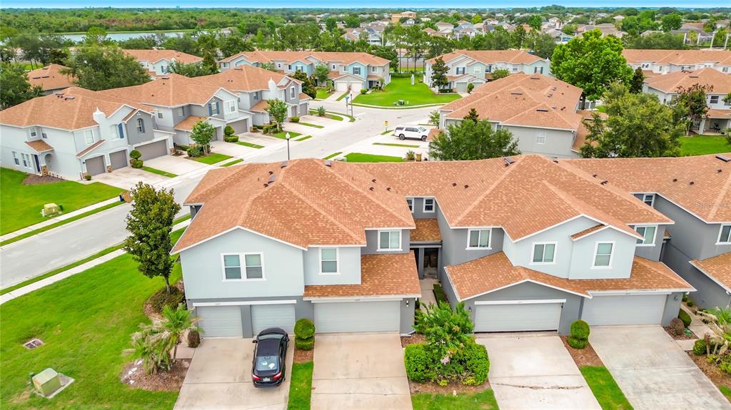 An aerial view of a multi-unit townhouse complex with light gray siding and brown roofs — 1009 CHALCEDONY STREET, KISSIMMEE, FL