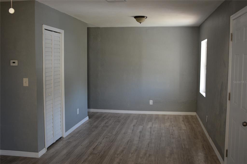 An empty room features gray walls, light wood-look flooring, a white closet, and a window — 1328 3RD STREET NE, WINTER HAVEN, FL