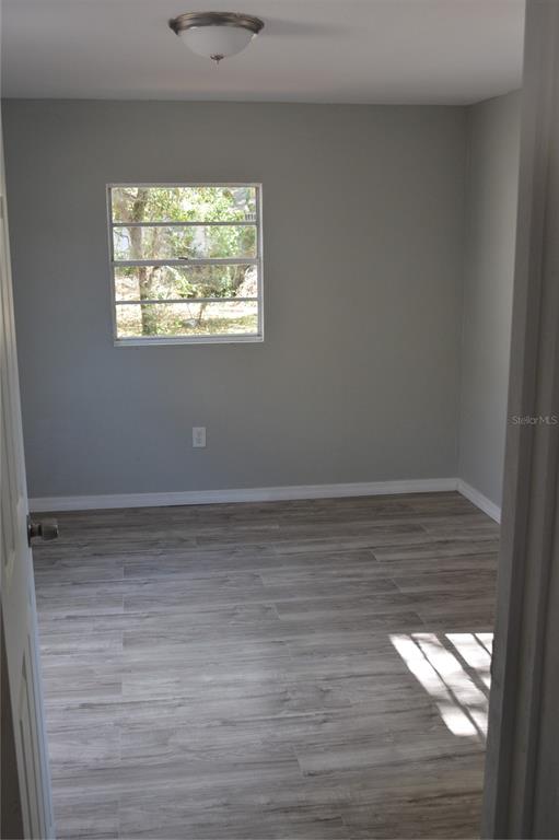 A small bedroom with gray walls, light wood-look flooring, and a single window — 1328 3RD STREET NE, WINTER HAVEN, FL