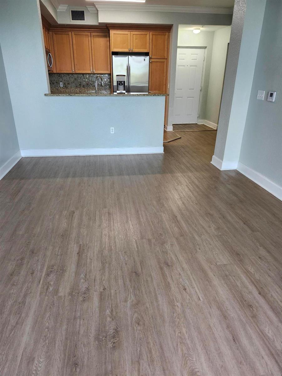 A view of a kitchen with wood cabinets and a breakfast bar overlooking a room — 1660 Renaissance Commons Boulevard # 2504, Boynton Beach FL 33426, BOYNTON BEACH, FL