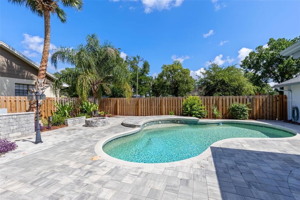 A backyard features a curved swimming pool, a stone fire pit, and a wooden fence — 351 NEEDLES TRAIL, LONGWOOD, FL