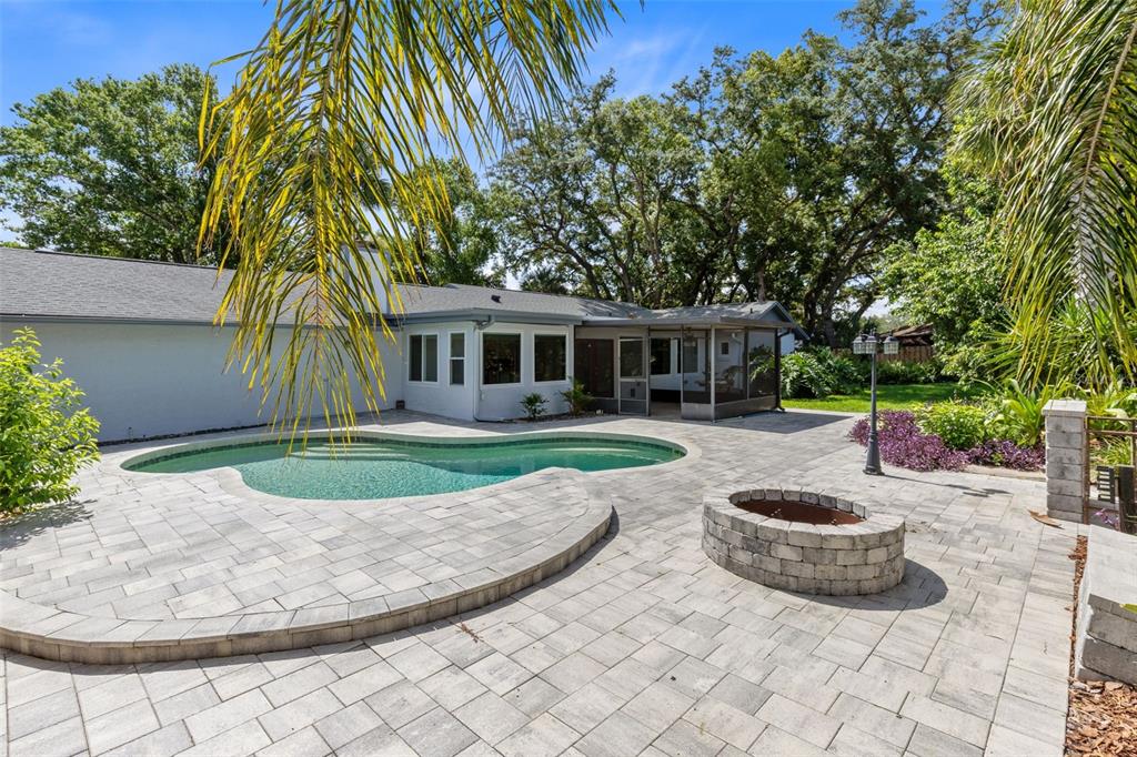 A backyard features a swimming pool, a stone fire pit, and a paved patio area — 351 NEEDLES TRAIL, LONGWOOD, FL