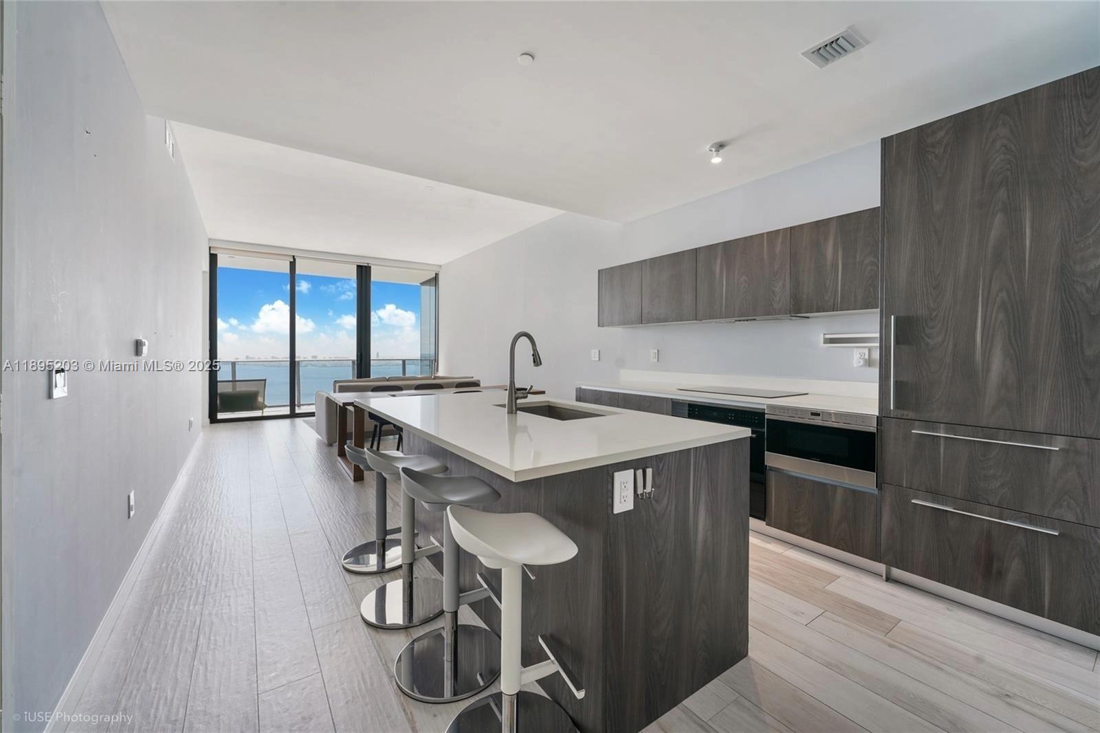 A modern kitchen features a central island with bar seating and dark wood cabinetry — 480 NE 31st St # 4106, Miami FL 33137, MIAMI, FL