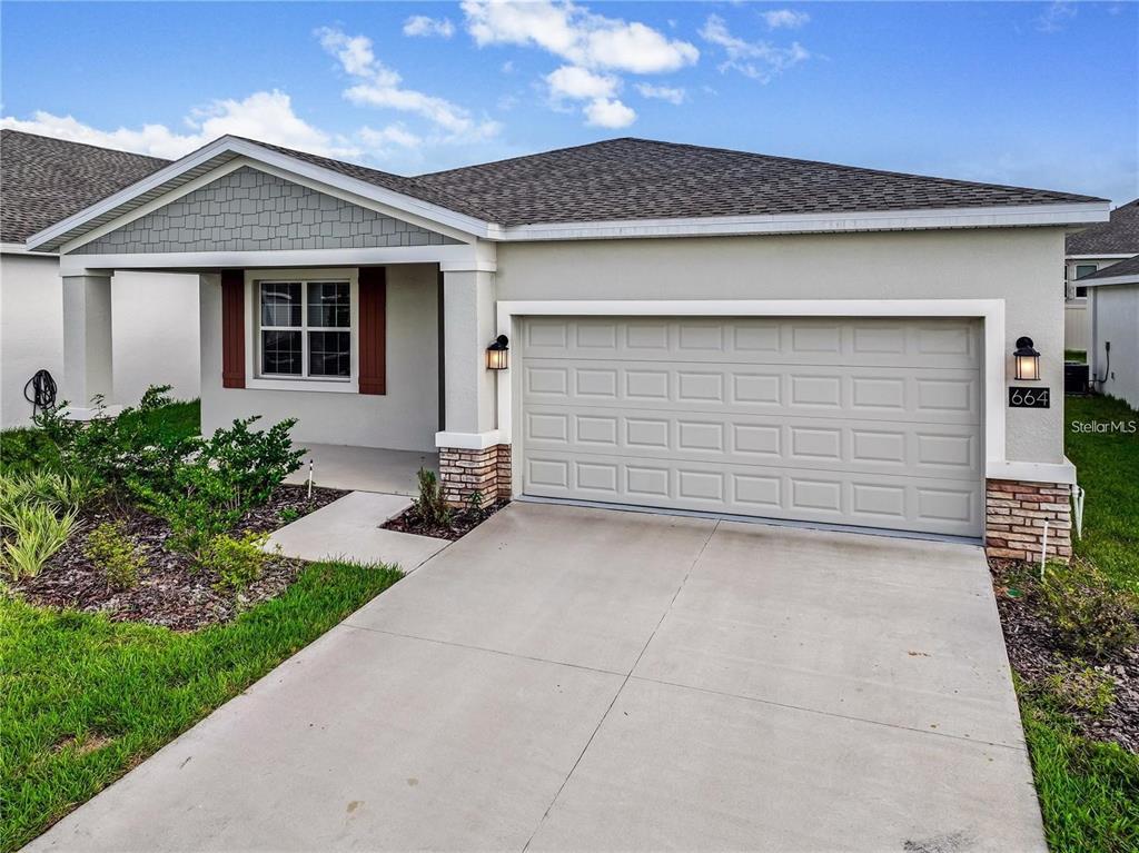 A single-story house with a gray garage door, stone accents, and a covered front porch — 664 TANARO LANE, HAINES CITY, FL