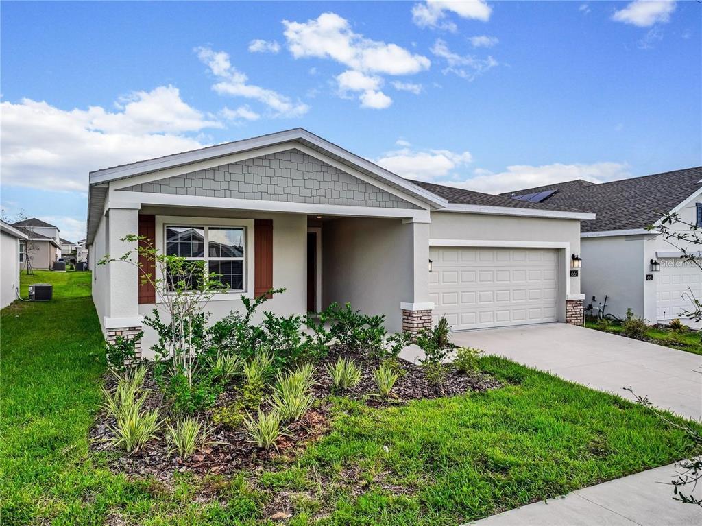A single-story suburban house features a tan stucco exterior, a gray shingled roof, and a garage — 664 TANARO LANE, HAINES CITY, FL