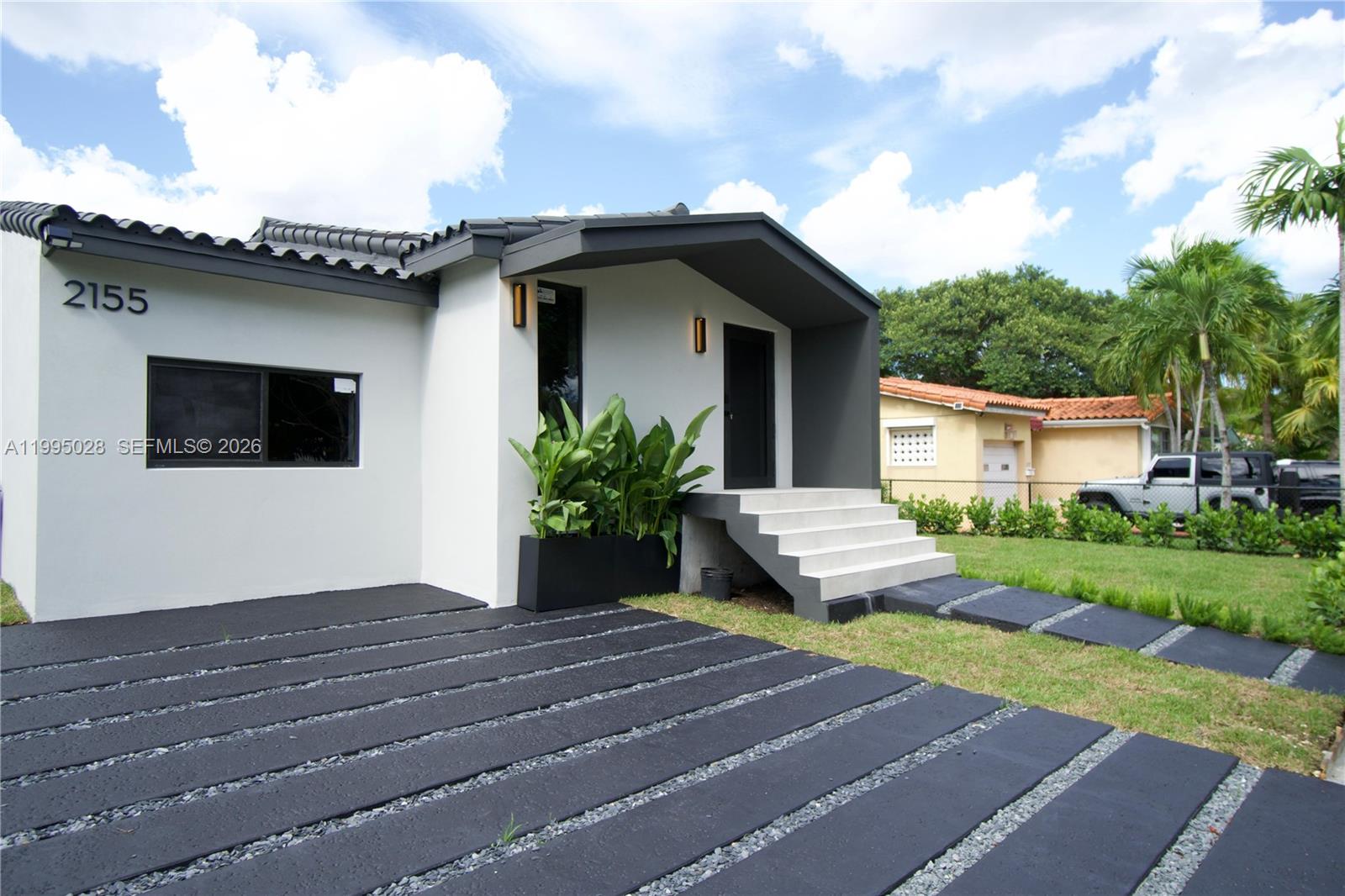 A modern white house features a dark gray entryway, concrete steps, and a paved driveway — 2155 SW 25th Ter, Miami FL 33133, MIAMI, FL