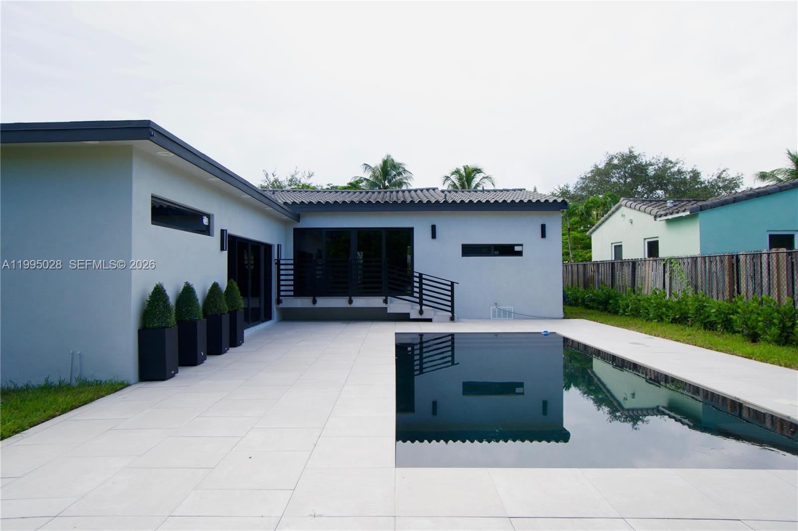 A modern house exterior features a patio, a rectangular swimming pool, and black planters — 2155 SW 25th Ter, Miami FL 33133, MIAMI, FL