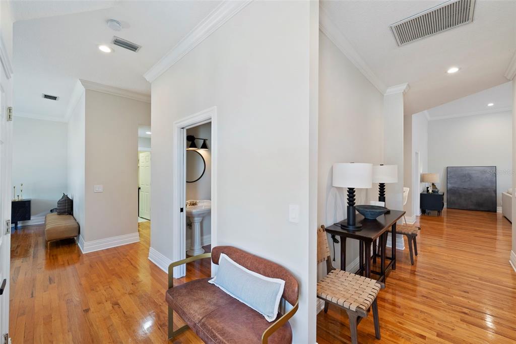 A hallway with hardwood floors leads to a bathroom and an open living area — 2504 W TENNESSEE AVENUE UNIT A, TAMPA, FL