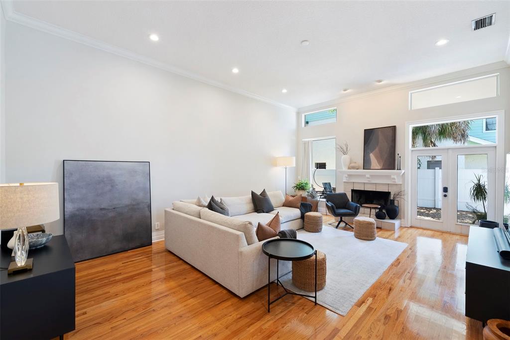 A living room with hardwood floors, a sectional sofa, a fireplace, and glass patio doors — 2504 W TENNESSEE AVENUE UNIT A, TAMPA, FL